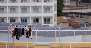 Temiz giysilerin kurutulduğu ve bir İspanyol apartman bloğunun tepesindeki çamaşır ipine tutturulduğu yüksek katlı binanın tepesindeki kuru havanın rüzgarla estiğini gösteren bir görüntü.