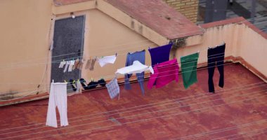 Temiz giysilerin kurutulduğu ve bir İspanyol apartman bloğunun tepesindeki çamaşır ipine tutturulduğu yüksek katlı binanın tepesindeki kuru havanın rüzgarla estiğini gösteren bir görüntü.
