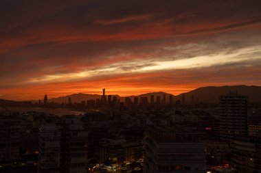 Benidorm İspanya, 20 Mart 2025: İspanya 'nın eski Benidorm kasabasında güneşin batışının fotoğrafı gökyüzünde bulutlarla birlikte gökyüzünde yükselen daireler boyunca uzanan güzel kırmızı güneşi gösteriyor