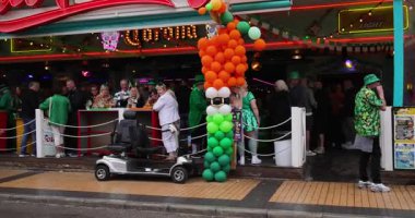 Benidorm İspanya, 17 Mart 2025: İspanya 'daki Benidorm kasabasının görüntüleri, yağmurlu bir günde barların ve barların önünde İrlanda bayramını el sallayan ve kutlayan insanları gösteriyor.