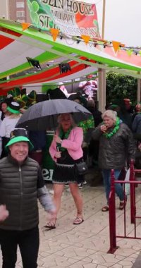 Benidorm İspanya, 17 Mart 2025: İspanya 'daki Benidorm kasabasının dikey portresi, insanların yağmurda barların ve barların önünde İrlanda bayramını kutladıklarını gösteriyor