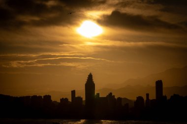 İspanya 'nın eski Benidorm kasabasında akşam vakti güneşin batışının fotoğrafı. Yazın gökyüzünde bulutların yükseldiği güzel kırmızı güneşi gösteriyor.