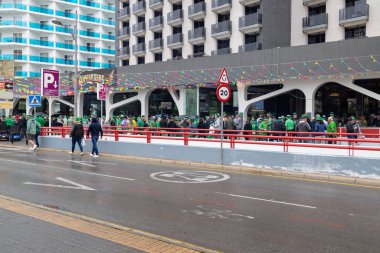 Benidorm İspanya, 17 Mart 2025: İspanya 'daki Benidorm kasabasının fotoğrafı, yağmurlu bir Mart ayında barların ve barların önünde Aziz Patrick Günü' nü kutlayan insanları gösteriyor.