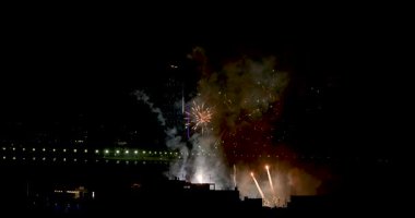 İspanya 'nın eski Benidorm kasabasının arka planında gece vakti bir İspanyol festivalini kutlamak için sahilin önünde havai fişekleri gösteren görüntüler.