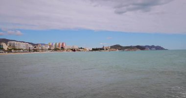 İspanya 'nın Villajoyosa kasabasındaki tipik bir İspanyol plajının yavaş çekim görüntüleri güneşli bir günde güzel bir sahili ve okyanusu gösteriyor.