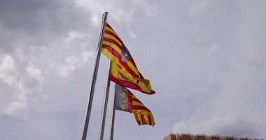 İspanya 'nın Alicante kentindeki Villajoyosa kasabasında güneşli bir günde İspanyol ve Valensiya toplumunun bayrağını gösteren 3 İspanyol bayraklı bir seçimin görüntüsü.