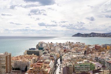 İspanya 'nın Benidorm kentinin havadan çekilmiş fotoğrafı, Platja de Ponent ya da Batı Sahili gezinti güvertesi olarak bilinen eski kentin arka planında dağlar ve bulutlar olduğunu gösteriyor.