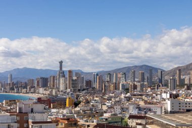 İspanya 'nın Benidorm kentinin havadan çekilmiş fotoğrafı, Platja de Ponent ya da Batı Sahili gezinti güvertesi olarak bilinen eski kentin arka planında dağlar ve bulutlar olduğunu gösteriyor.