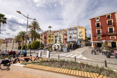 Villajoyosa İspanya, 15 Mart 2025: İspanya 'nın güzel bir kasabası olan Villajoyosa' nın fotoğrafı İspanyol köyünde yazın her iki tarafında renkli evler olan küçük bir caddeyi gösteriyor