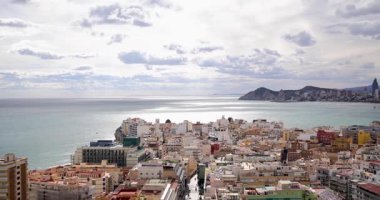 İspanya 'nın Benidorm kentinin havadan çekilmiş görüntüleri, arka planda dağların ve bulutların yanı sıra Platja de Ponent veya West Beach gezinti güvertesi olarak bilinen eski şehir plajını gösteriyor.