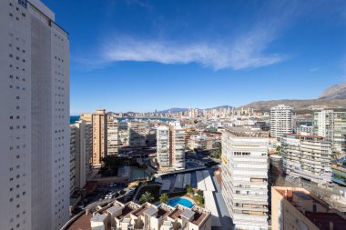 Benidorm İspanya, 10 Mart 2025: İspanya 'nın eski Benidorm kasabasına bakan fotoğraf, güneşli bir günde yüksek katlı apartmanlar, Poniente Sahili ve arka planda dağları gösteriyor