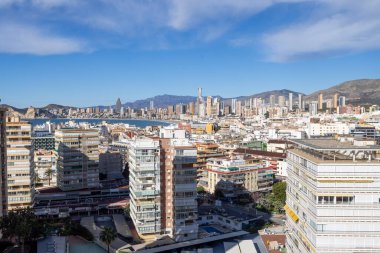Benidorm İspanya, 10 Mart 2025: İspanya 'nın eski Benidorm kasabasına bakan fotoğraf, güneşli bir günde yüksek katlı apartmanlar, Poniente Sahili ve arka planda dağları gösteriyor