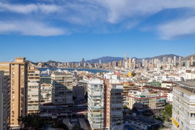 Benidorm İspanya, 10 Mart 2025: İspanya 'nın eski Benidorm kasabasına bakan fotoğraf, güneşli bir günde yüksek katlı apartmanlar, Poniente Sahili ve arka planda dağları gösteriyor