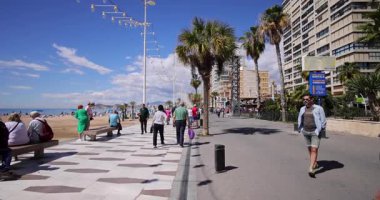 Benidorm İspanya, 27. Maç 2025: İspanya 'nın Benidorm kasabasının yavaş çekim görüntüleri güneşli bir günde Levante Sahili' nin yanında yürüyen insanları ve turistleri gösteriyor.