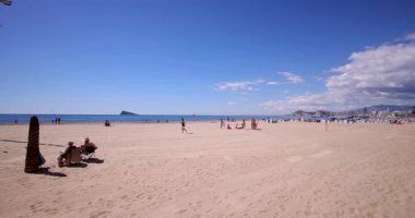 Benidorm İspanya, 27. Maç 2025: İspanya 'nın Benidorm kasabasının yavaş çekim görüntüleri, insanların kumlu Levante Sahili' nde ve okyanustaki Isla de Benidorm olarak bilinen adada dinlendiklerini gösteriyor.