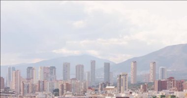 İspanya 'nın eski Benidorm kasabasını gösteren hızlandırılmış görüntüler İspanya' nın dağları ve arka planında yüksek katlı daireleri olan iki saatlik bir periyotta hareket eden bulutları gösteriyor.