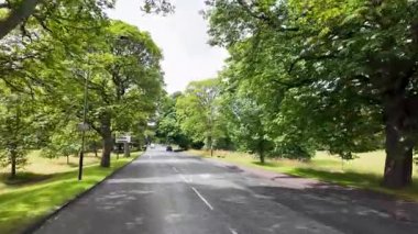 Harrogate Yorkshire UK, 2 Temmuz 2025: Harrogate kasabasının sokaklarının yavaş çekim görüntüleri, güneşli bir yaz gününde yolun her iki tarafında da yeşil bir sokak olduğunu gösteriyor