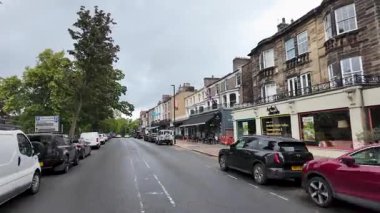 Harrogate Yorkshire UK, 2 Temmuz 2025: Harrogate kasabasının caddelerinin yavaş çekim görüntüleri, yaz mevsiminde yol kenarında dükkanları ve restoranları olan ana yolu gösteriyor