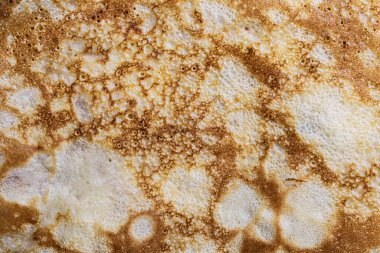 Pancake surface texture and pattern. Close-up of thin hot pancakes in a plate. Traditional rustic food. Graphic resource. Table top view.