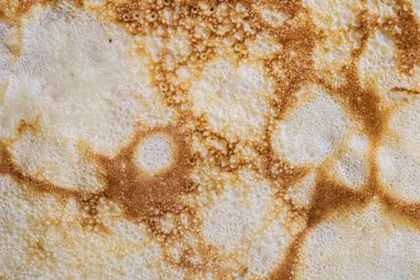 Pancake surface texture and pattern. Close-up of thin hot pancakes in a plate. Traditional rustic food. Graphic resource. Table top view.