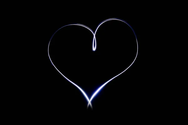 Light heart symbol on isloted black background. Long exposure creative photography. Light painting. Love and romance emblem. Glowing and bright effect.