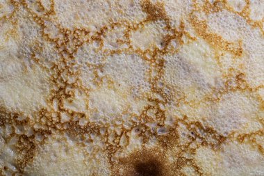 Pancake surface texture and pattern. Close-up of thin hot pancakes in a plate. Traditional rustic food. Graphic resource. Table top view.