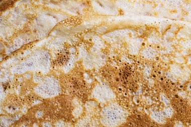 Pancake surface texture and pattern. Close-up of thin hot pancakes in a plate. Traditional rustic food. Graphic resource. Table top view.