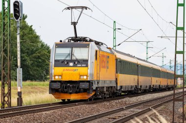 Komarom, Macaristan - 14 Haziran 2023: Regiojet Bombardier Traxx. Uluslararası ve bölgesel demiryolu taşımacılığı. Yolcu yük treni istasyona ayarlandı. Toplu taşıma.