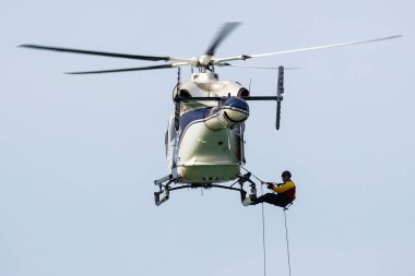 Zamardi, Hungary - September 16, 2020: Hungarian air police MD900 Explorer helicopter flying operation. SAR Search and rescue mission with rope. clipart