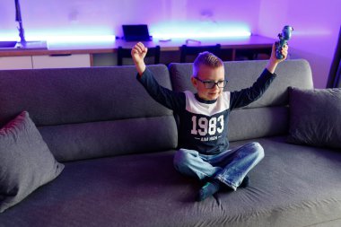 Little boy Danya plays on a game console. Emotionally reacts to victory and defeat.