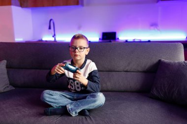 Little boy Danya plays on a game console. Emotionally reacts to victory and defeat.