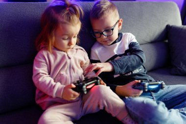 Older brother teaches younger sister to play the console. Children are emotionally happy when they win and sad when they lose.