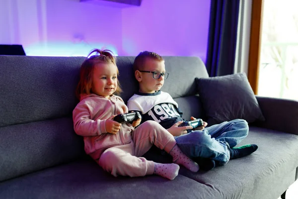 Older brother teaches younger sister to play the console. Children are emotionally happy when they win and sad when they lose.