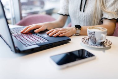 Bir kız kahve dükkanında bir fincan kahve eşliğinde programlama öğreniyor. Uzaklık öğrenimi