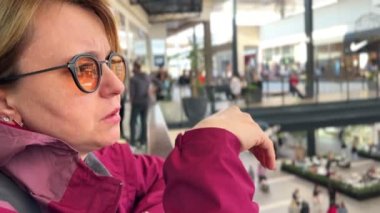 Sarı gözlüklü genç sarışın kadın dalgın dalgın bakıyor.