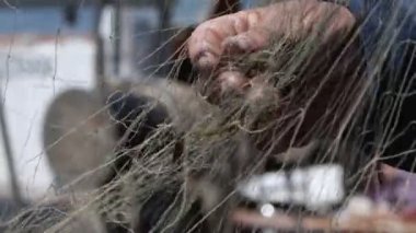 Balıkçı rıhtımdaki balıkçı teknesinde balık ağlarını tamir ediyor.