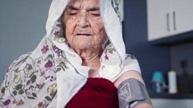 Yaşlı Müslüman bir kadın kendini kötü hissettiğinde tansiyonunu ölçer.