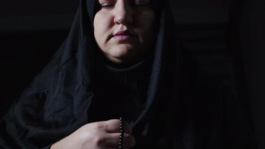 Siyah dua kıyafetleri ve türban takan genç Müslüman kadın.