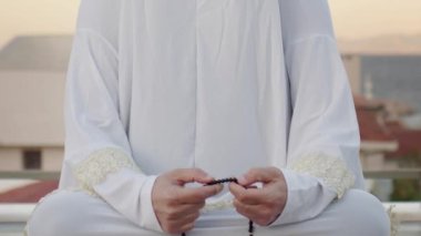 Beyaz elbiseli kadın tespihle dua ediyor. 