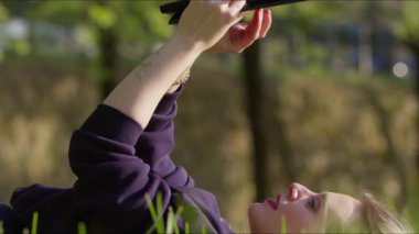 Genç Kadın Doğada Çimen Üzerine Dijital E kitabını kullanıyor