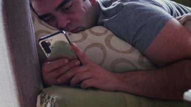 Uykucu Adam cep telefonuna bakıyor Koltukta yatıyor