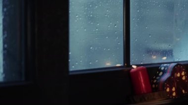 Kutsal Noel arifesi dekorasyon kutlaması ve hediye kutuları mum ışığında yağmurlu bir günde pencere camının yanında.