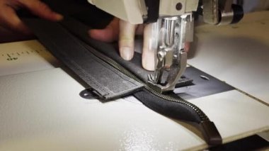 Terzi dükkanında dikiş makinesiyle kalın kumaşa fermuar dikiyorum.