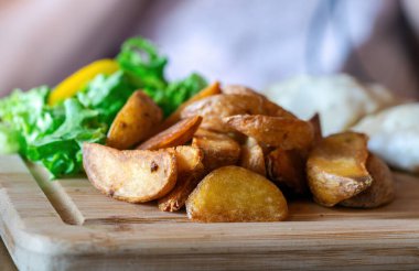 Patates kızartması ahşap tabakta sıkışıyor.