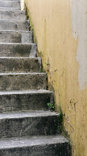 Vertical image of old weathered, worn concrete exterior staircase with painted brick wall to side. High quality photo