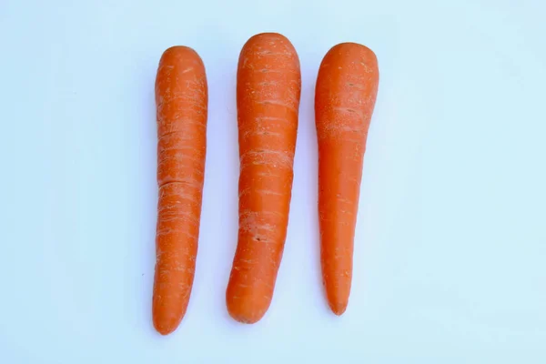 Stock image Three assorted orange carrots lying on a plain white background. High quality photo