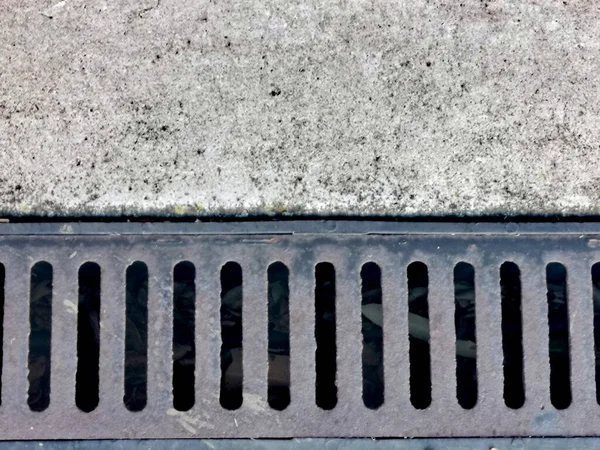 Gri benekli betonun yanında eski karanlık metal drenaj ızgarasının arka planı. Kopyalama alanı olan yüksek kaliteli fotoğraf.