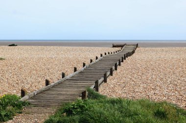 Yıpranmış ahşap tahta yürüyüşü ya da otlak alanından uzak sahillere kadar uzanan patika..
