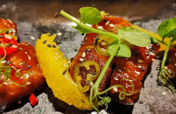 Akçaağaç şurubunda kızarmış somon bifteği bezelye filizleri ve portakal dilimleriyle süslenmiş.