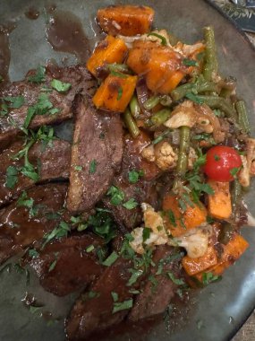 Tatlı patates, domates ve maydanozla süslenmiş yeşil fasulyeli nefis pişirilmiş ördek. Yüksek kalite fotoğraf